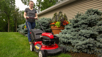 woman pushing red push mower
